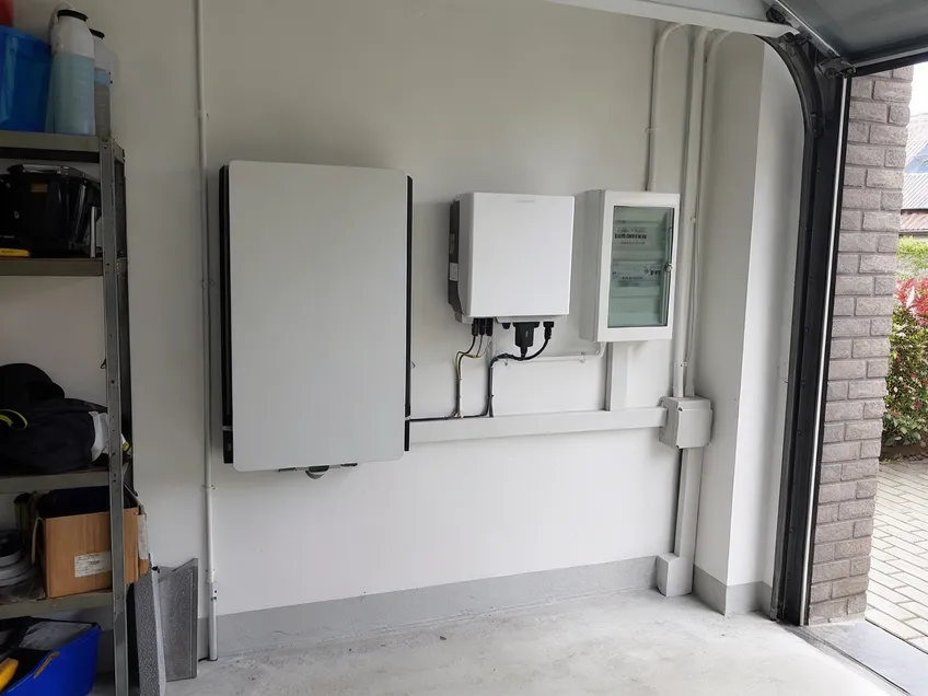 Wall mounted solar battery installed in a European residential garage alongside a hybrid inverter
