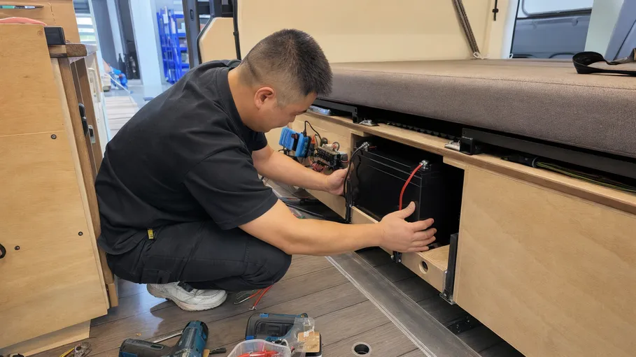 Camper van conversion shop installing LiFePO4 battery under bench seat
