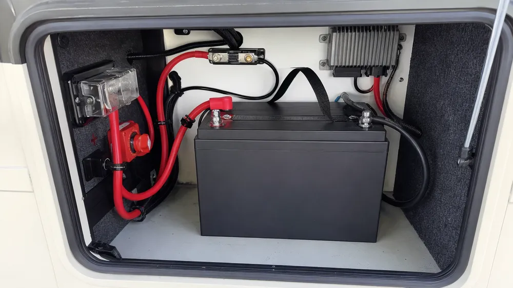 LiFePO4 battery installed in RV battery compartment showing terminal connections and cable routing